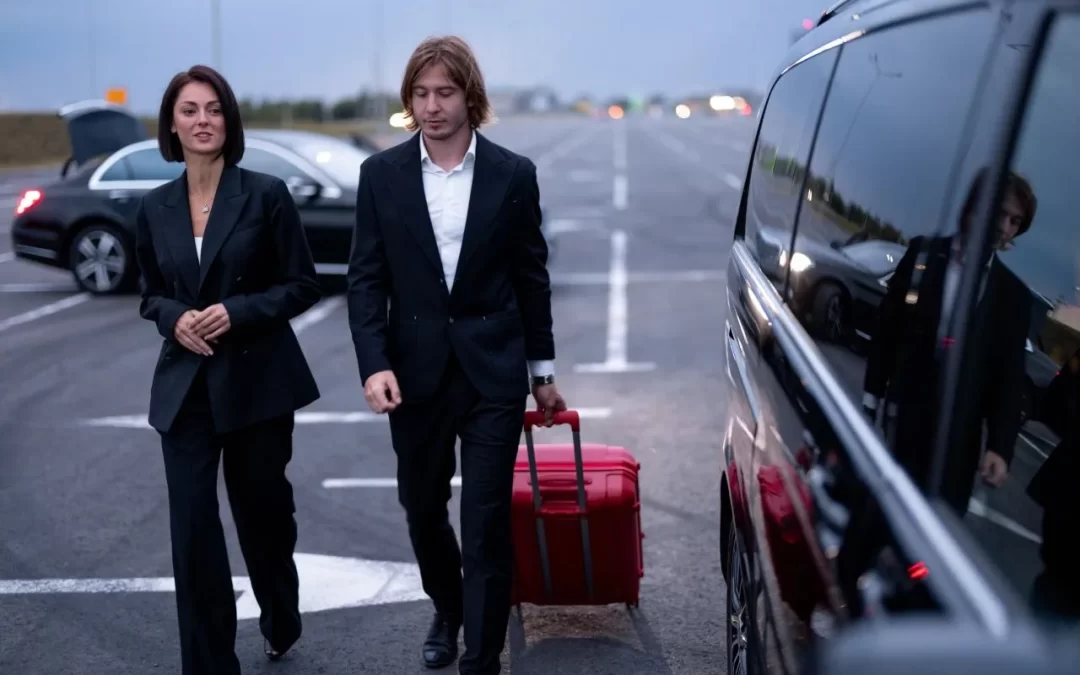 Business colleagues walking with a rolling suitcase beside a passenger van