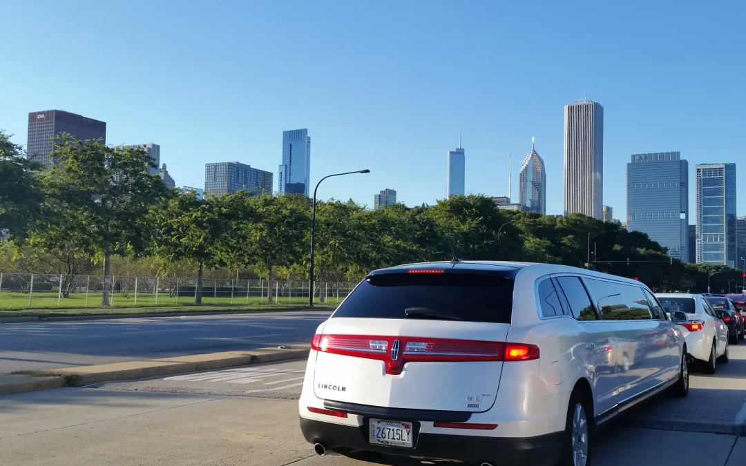 White stretch limousine in traffic with Chicago skyline and park trees behind it